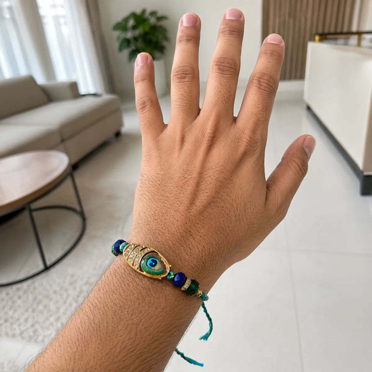 Evil eye rakhi worn on a hand in a contemporary living room.