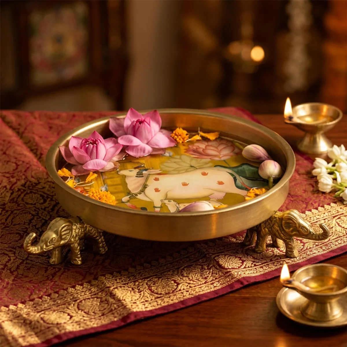 Gold Urli with elephant bases, floral artwork and floating flowers on a festive table