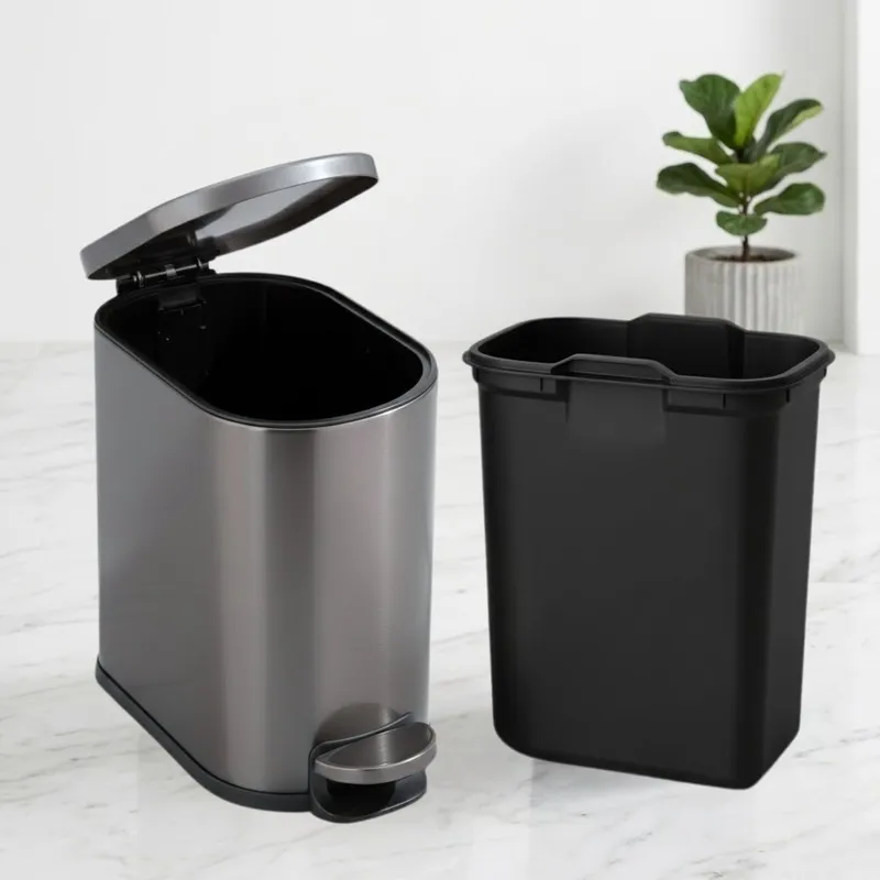 Black metal pedal dustbin with removable inner bucket placed beside it