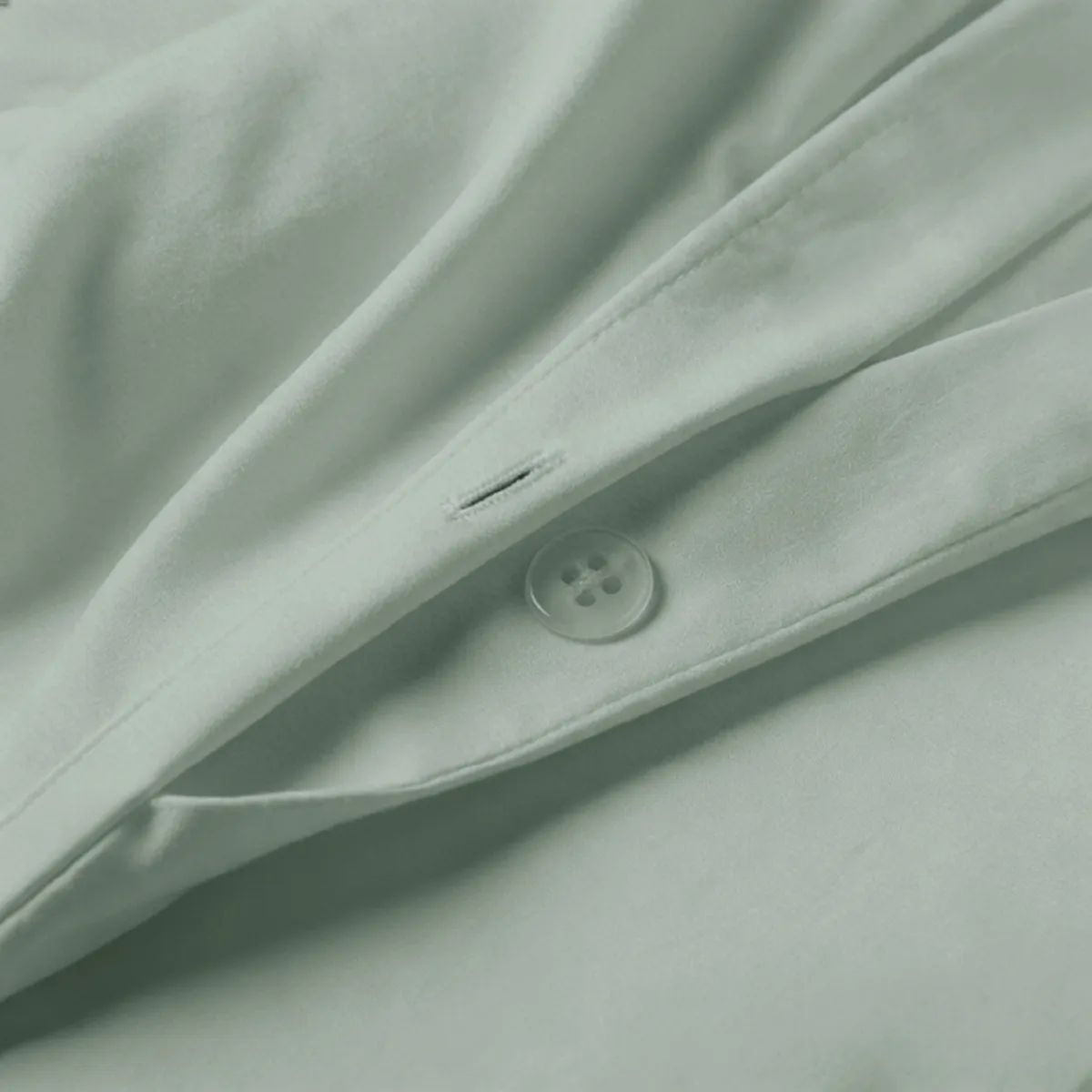 Close-up of sage-green cotton duvet cover fabric and stitching