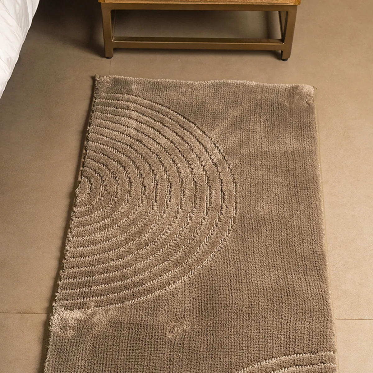 Close view of the beige runner rug showing its raised concentric arc design.