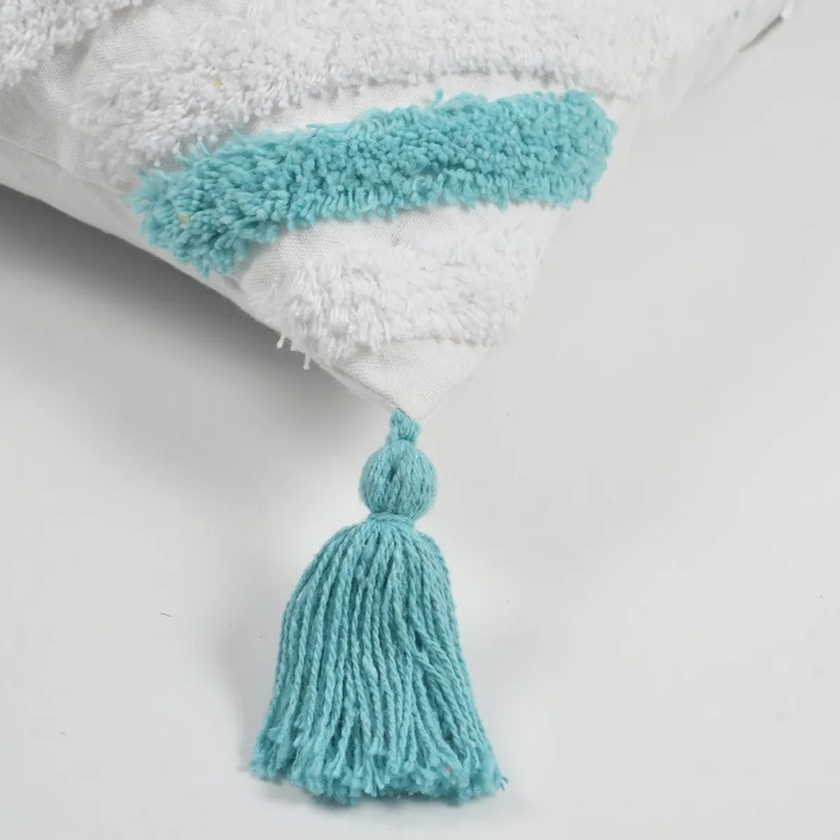 Close-up of a blue tassel and textured tufted trim on a cushion cover