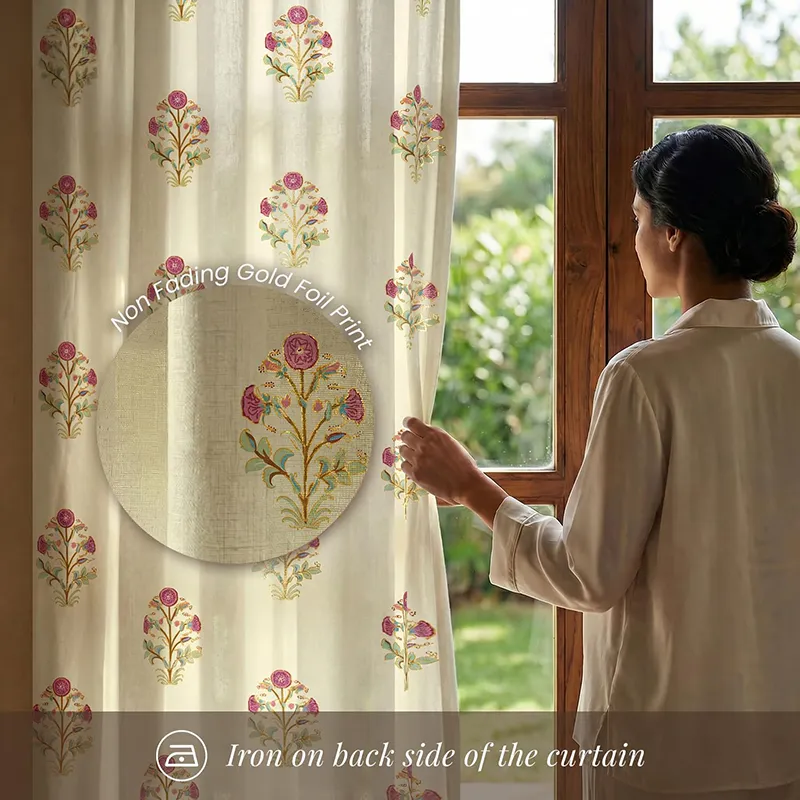Close view of floral printed curtain beside a window with a person holding the fabric