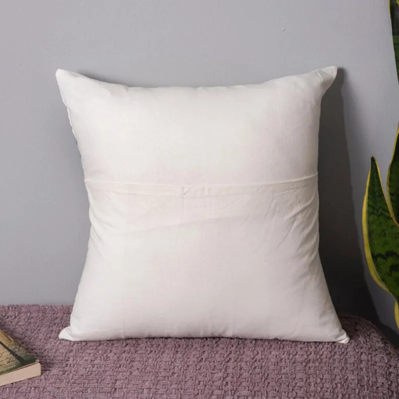 Back view of a plain white cushion cover on a bench beside a plant.