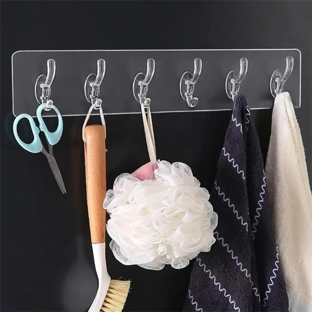 Transparent six-hook strip holding scissors, brushes, a bath sponge and towels