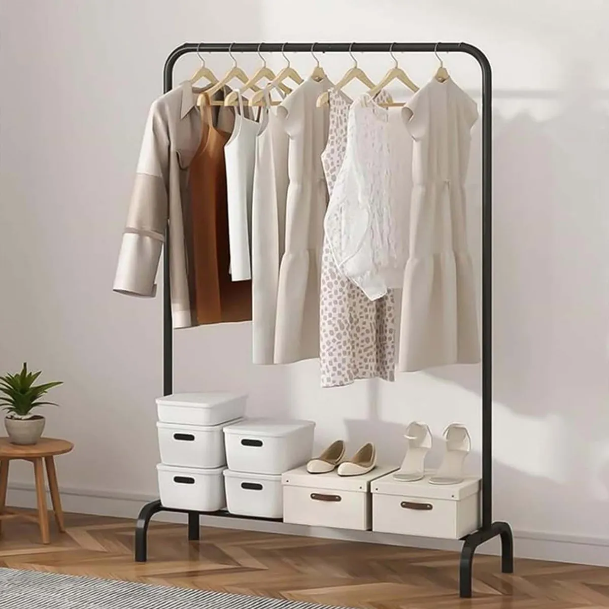 Black metal clothes rack with hanging rail and lower shelf in a room setting