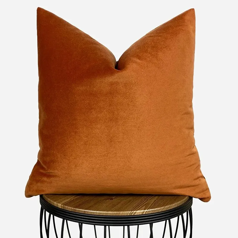 Single rust velvet square cushion cover on a round stool