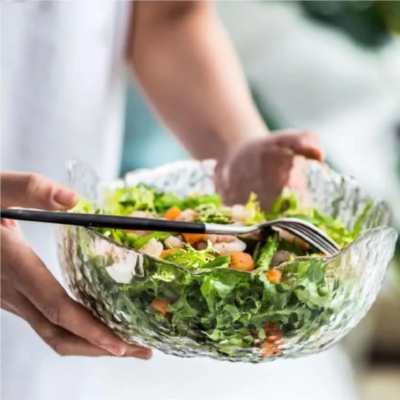 Large transparent textured glass bowl filled with salad and held in hands