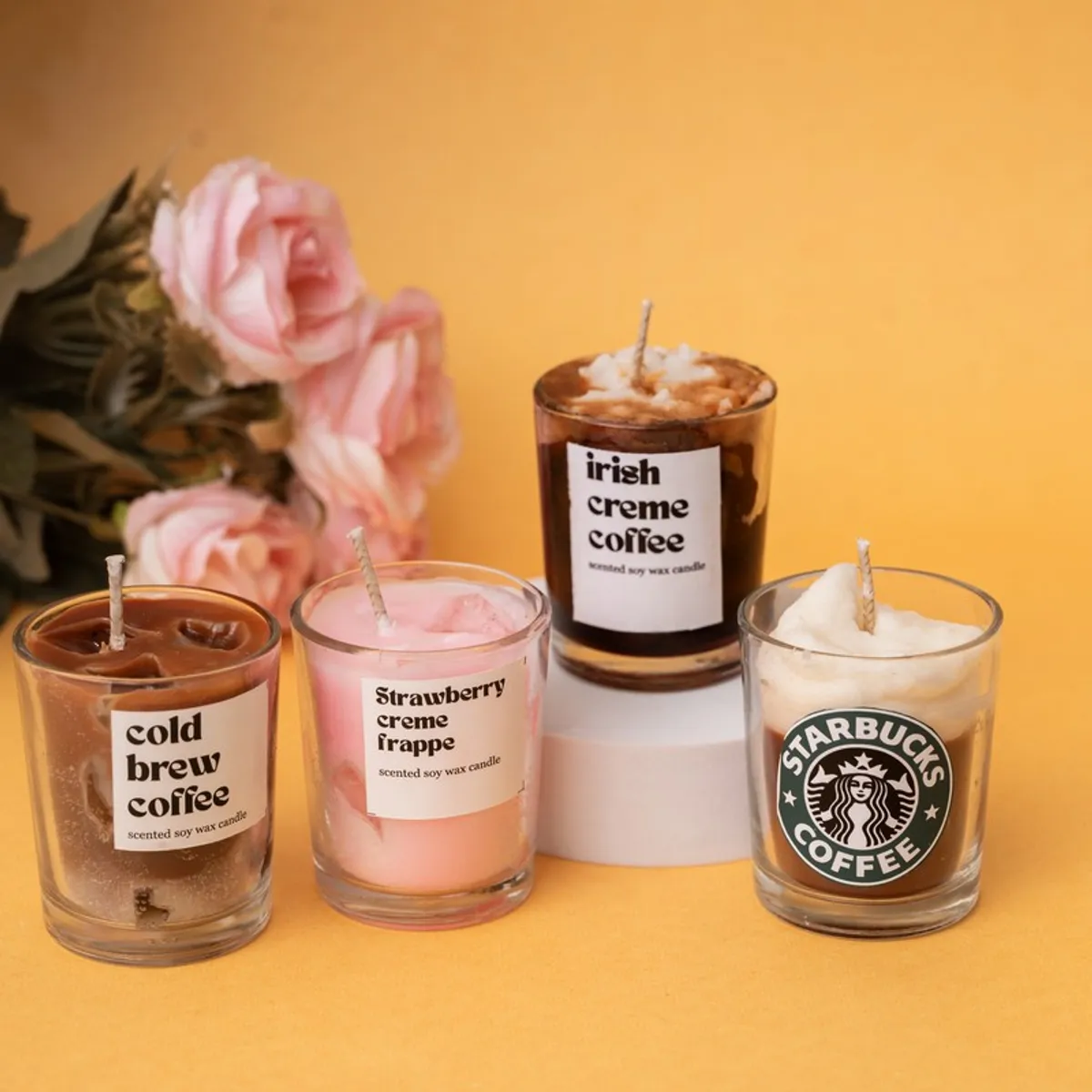 Four brown, pink and white scented candles displayed together against a warm background.