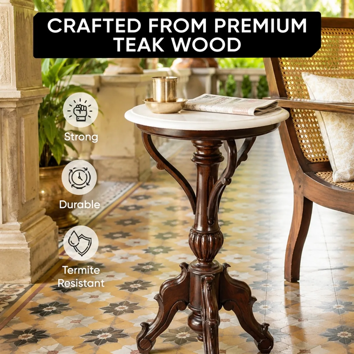 Brown carved side table with round white top in a verandah setting