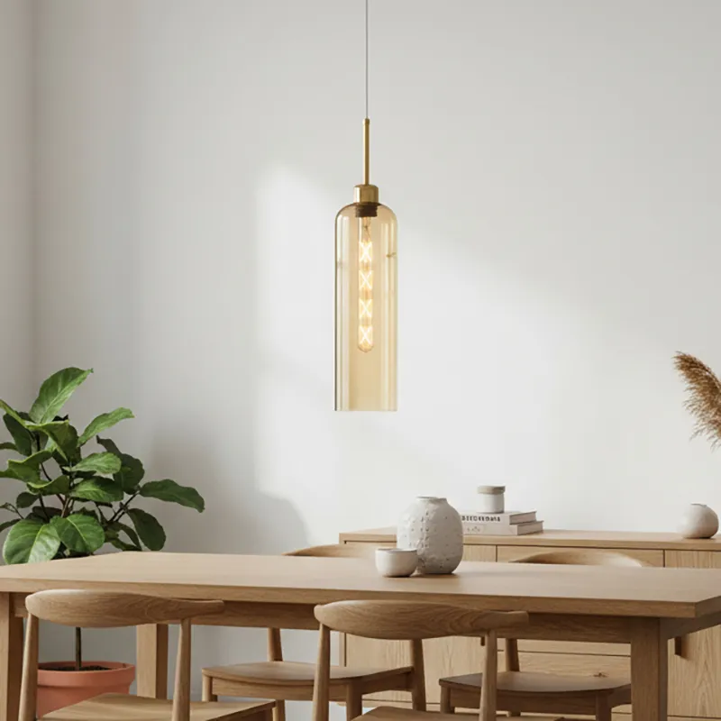 Amber cylindrical pendant lamp hanging above a light wood dining table