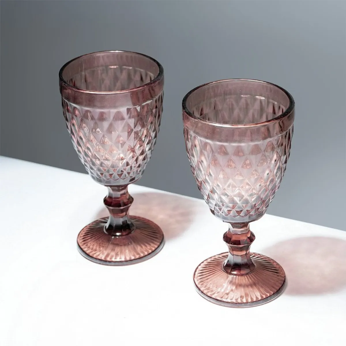 Two pink textured stemmed wine glasses in close-up