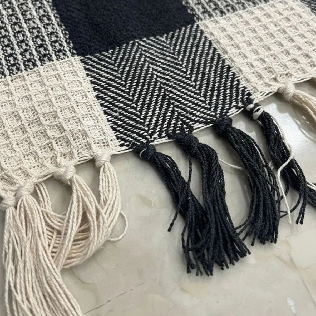 Close-up of the throw's textured black and white pattern with fringed edging