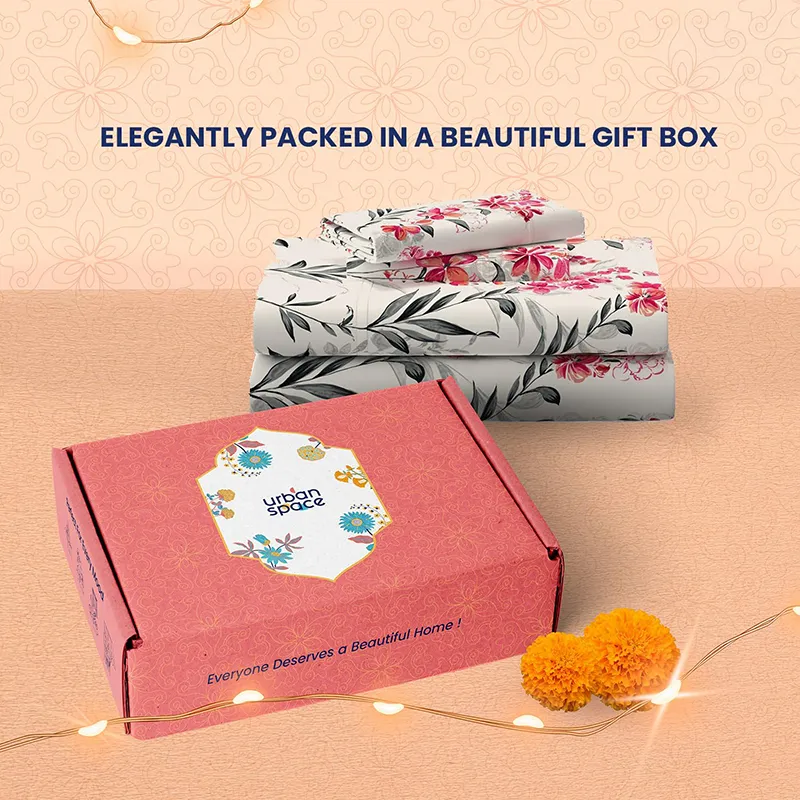 Folded floral bedsheet placed beside a pink branded box