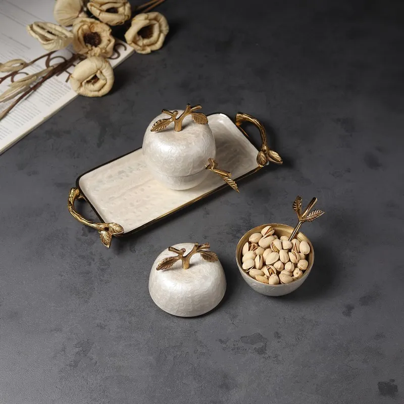 Apple-shaped jars and tray styled with dry fruits on a dark tabletop