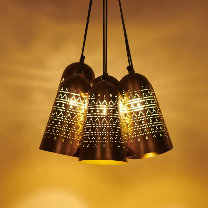 Close-up of glowing gold bell-shaped lamp shades with perforated geometric pattern