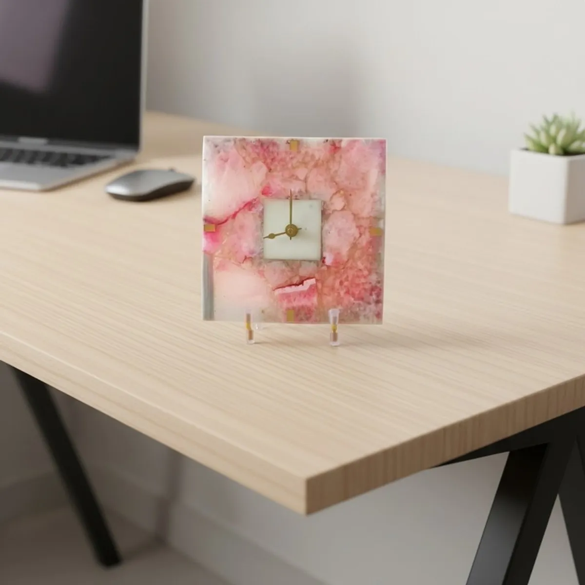 Pink agate table clock with stand placed on a light wood desk
