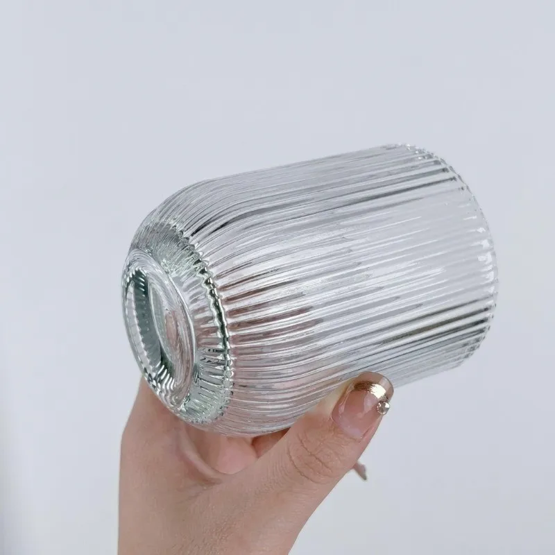Hand holding a clear glass with vertical lined detailing