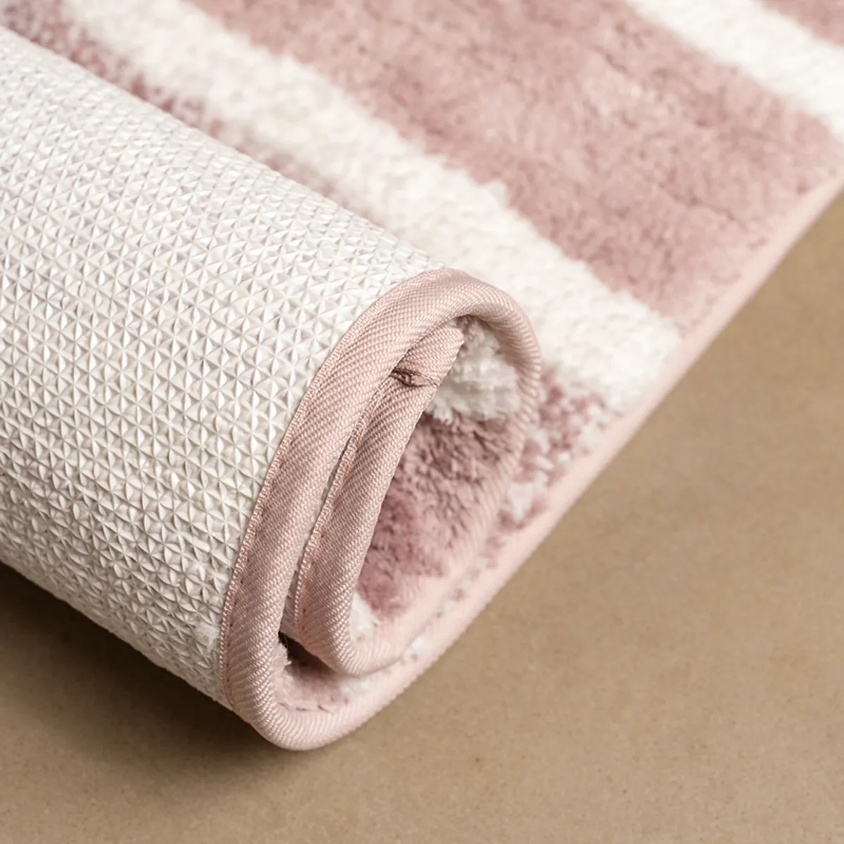 Rolled pink striped runner showing its textured anti-skid underside