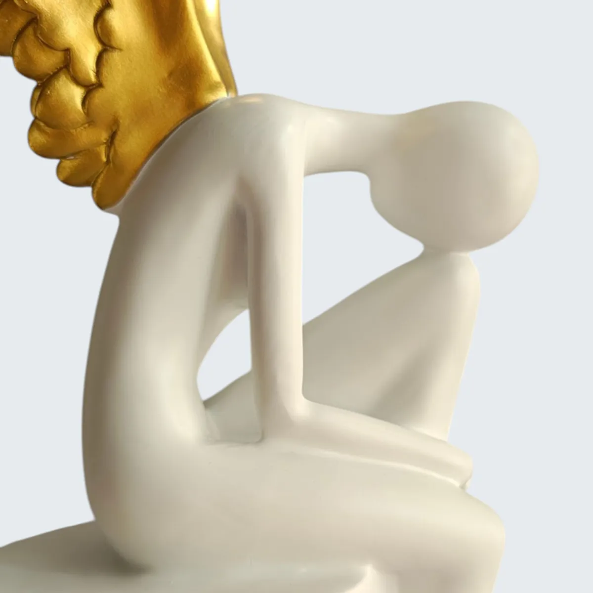 Close-up of the smooth white abstract figurine detail and gold wing