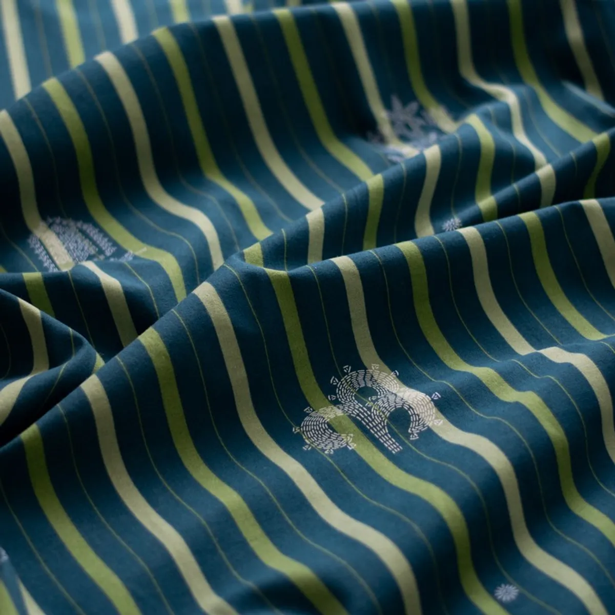 Close-up of blue and olive striped curtain fabric with white motifs and soft folds