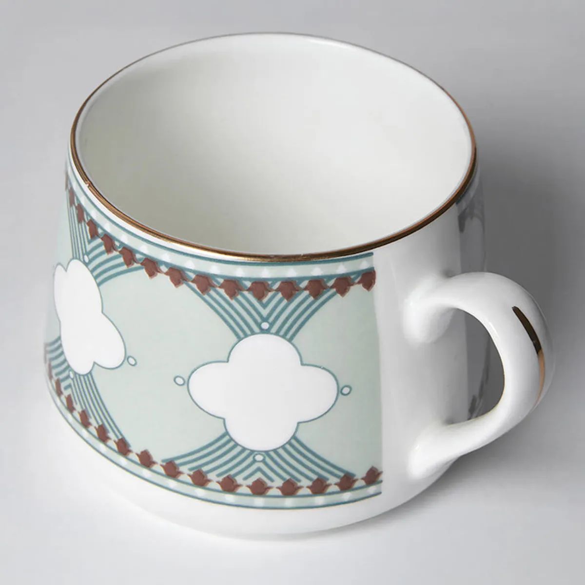 Close-up view of the patterned cup rim, handle and decorative teal design