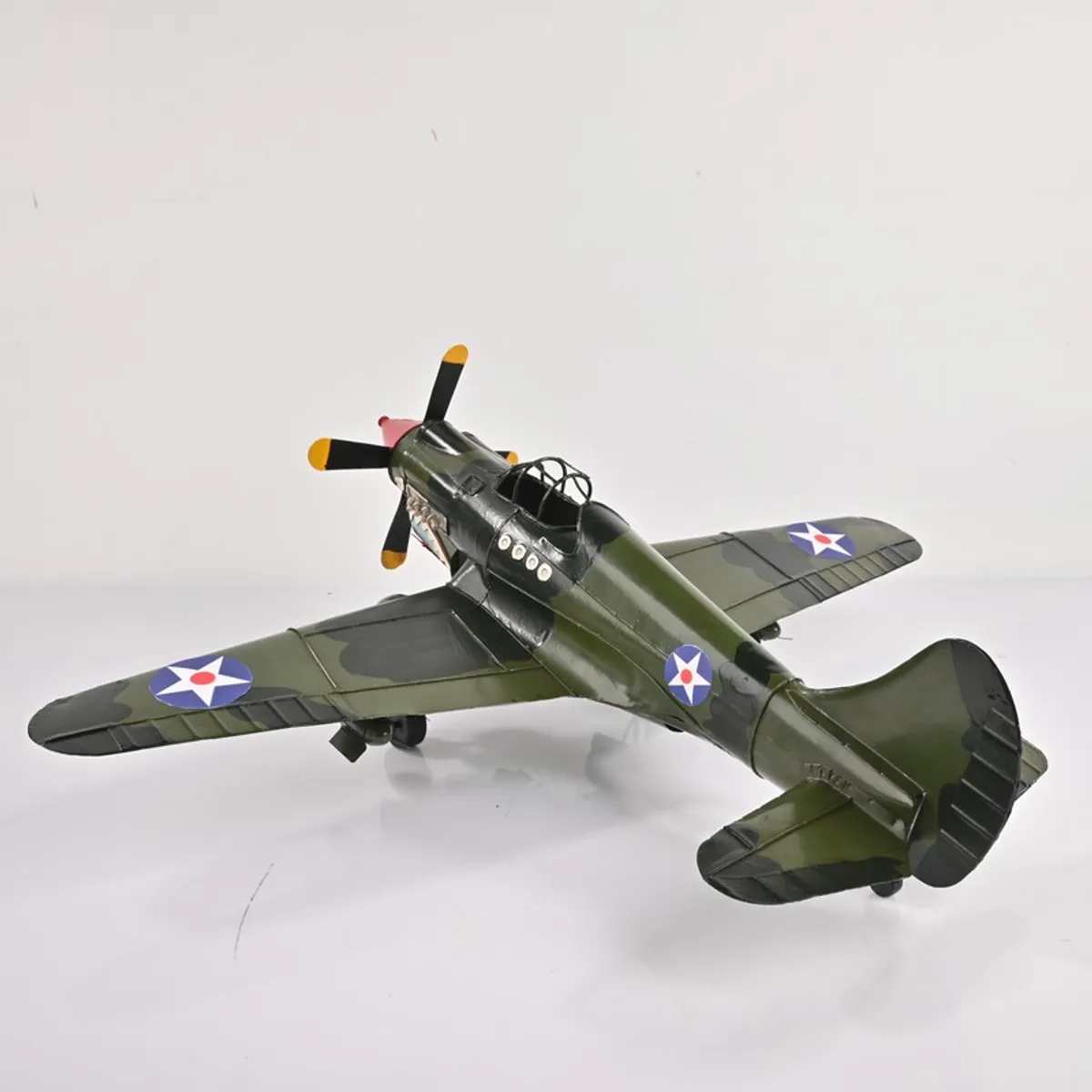 Top rear angle of olive green fighter plane decor piece on a white background