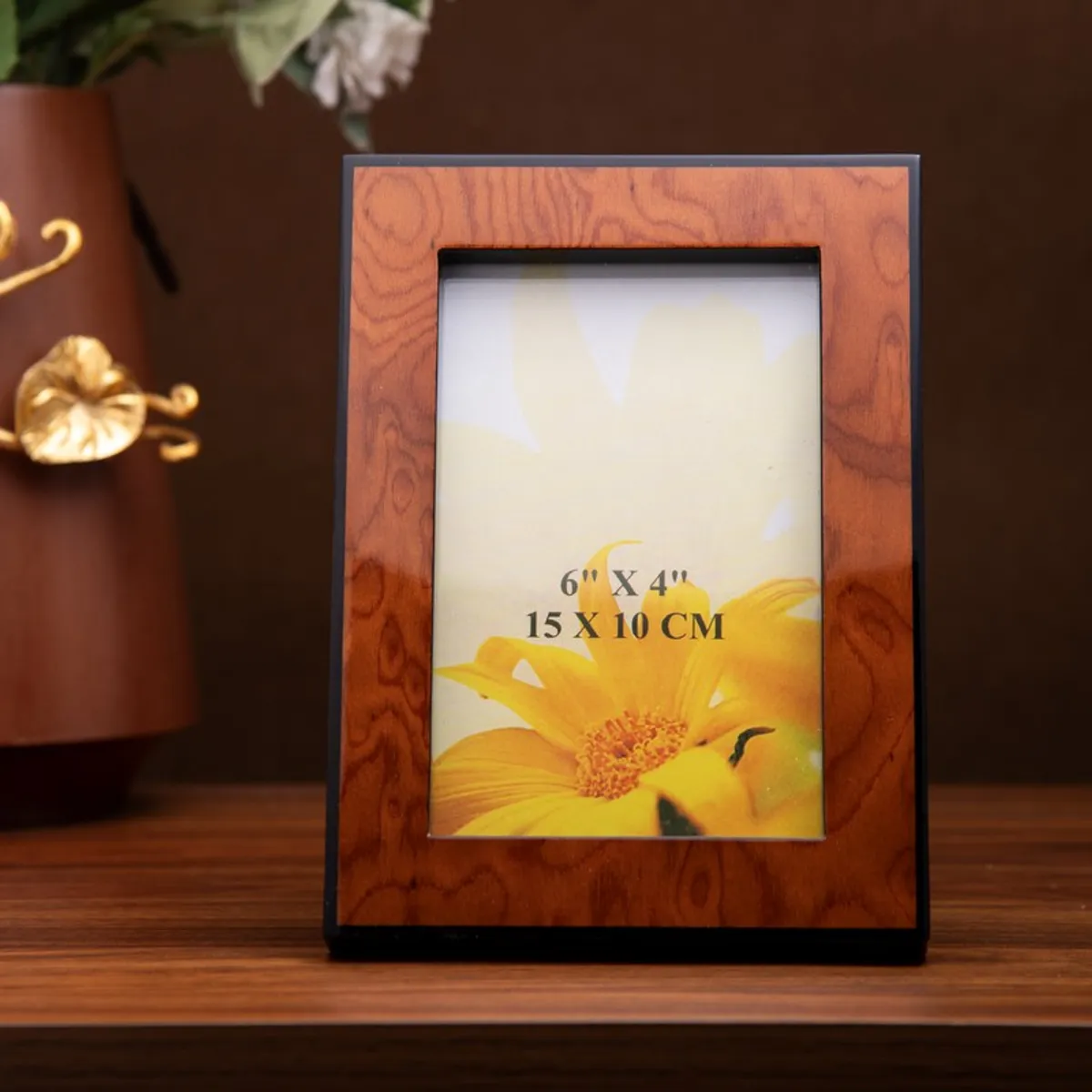 Front view of a brown rectangular photo frame with black border on a wooden table