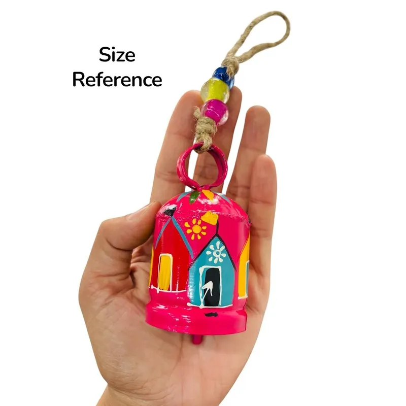 Close-up of a pink hand-painted hanging bell held in a hand