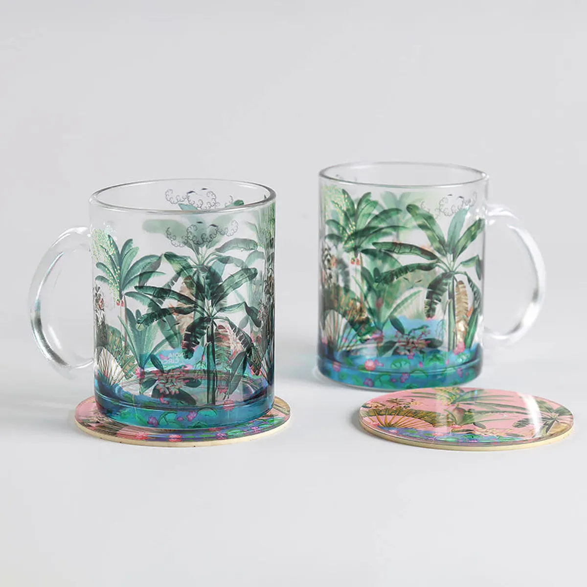Two tropical glass mugs placed on separate round coasters