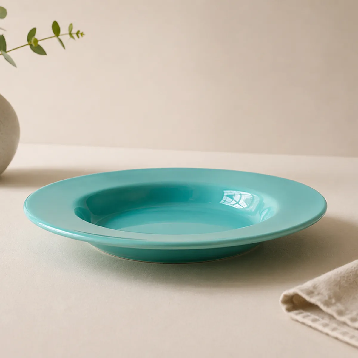 Side view of a glossy teal ceramic pasta plate