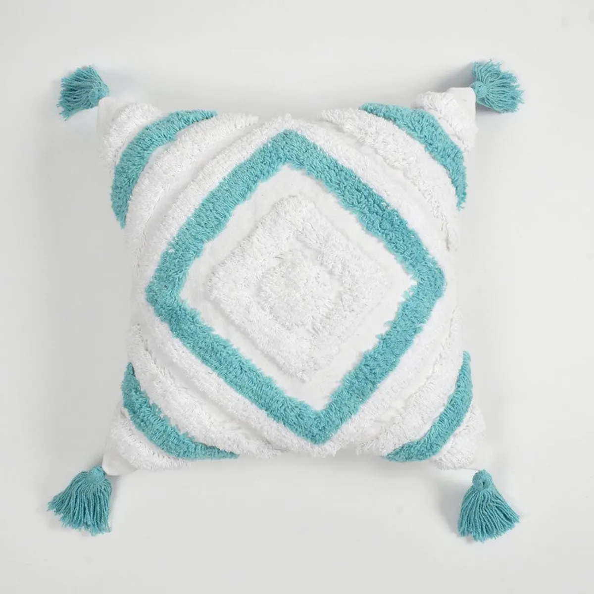 Front view of a white cushion cover with turquoise diamond pattern and tassels