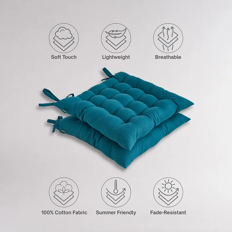 Two teal tufted chair pads stacked against a light background.