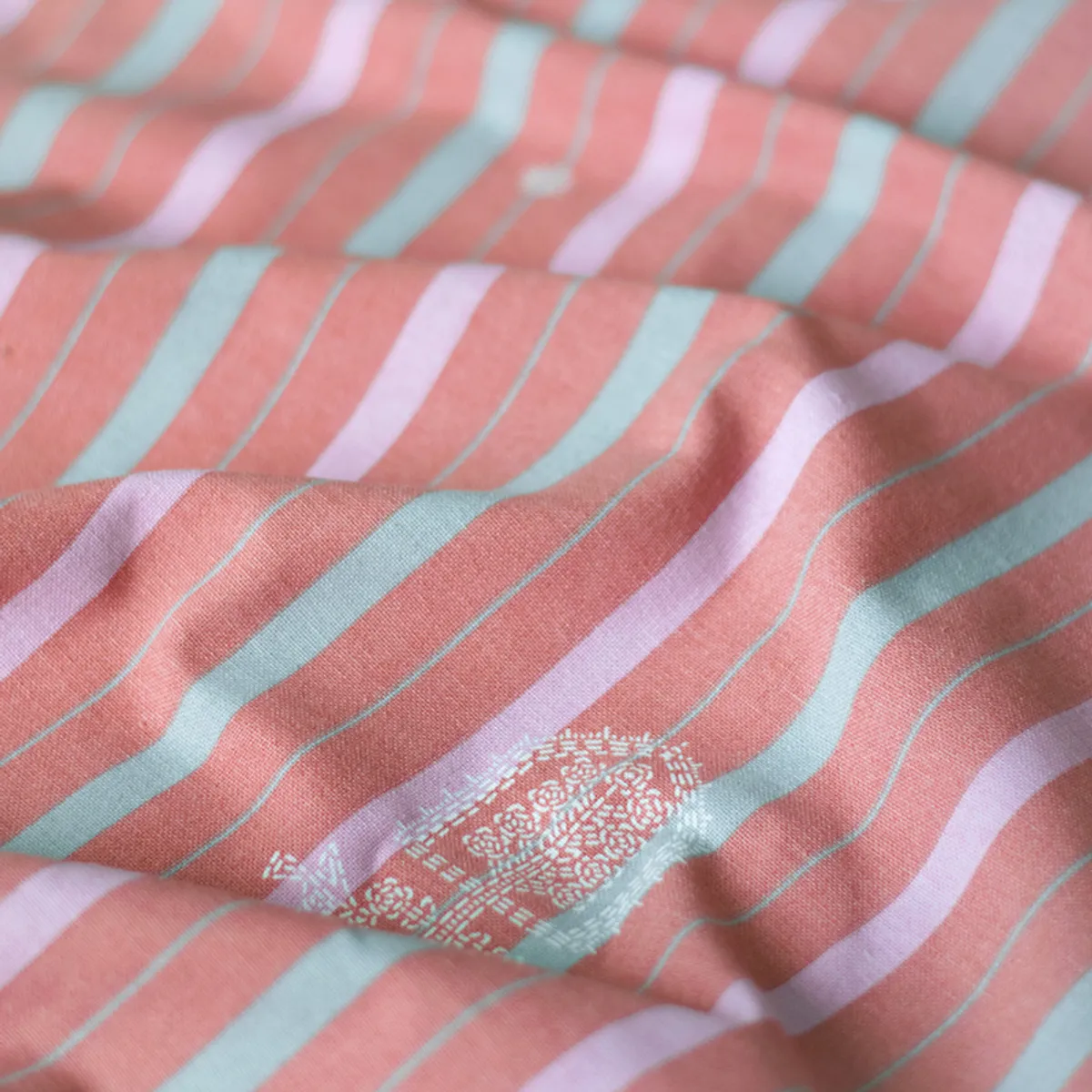 Close-up of soft pink striped curtain fabric with turquoise and lilac lines