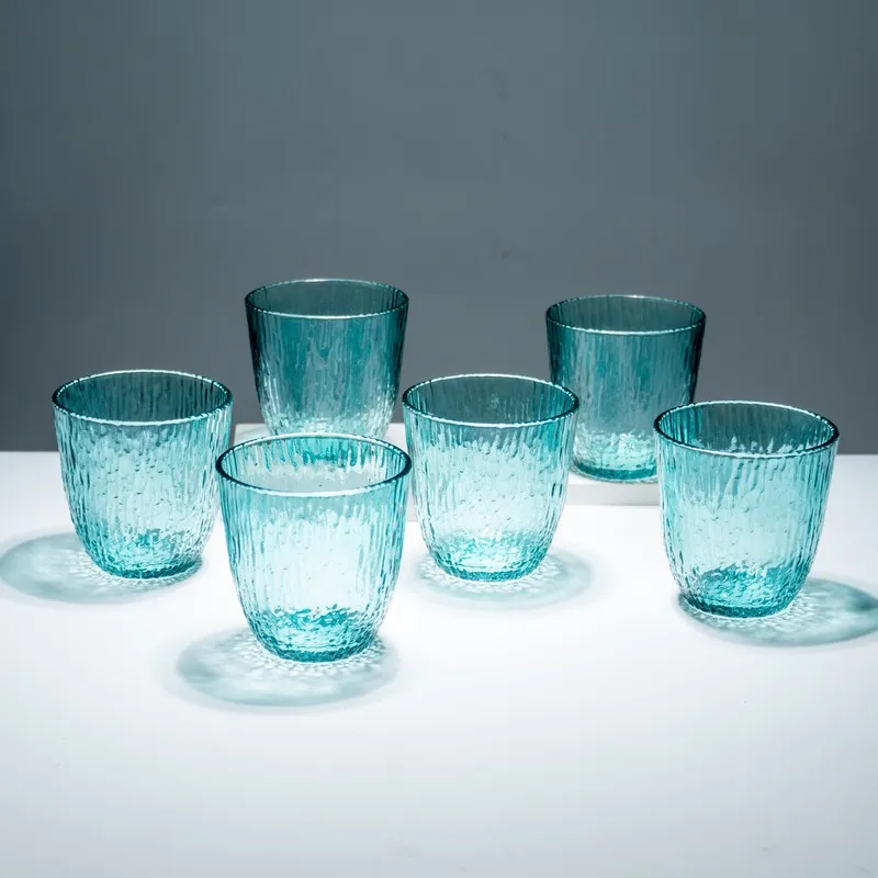 Set of six blue textured drinking glasses on a white surface