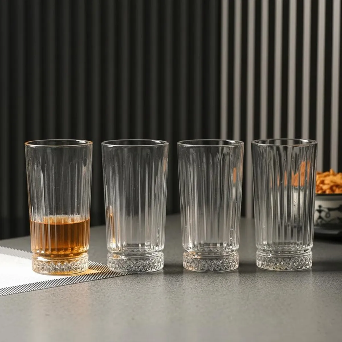 Four clear textured drinking glasses on a tabletop