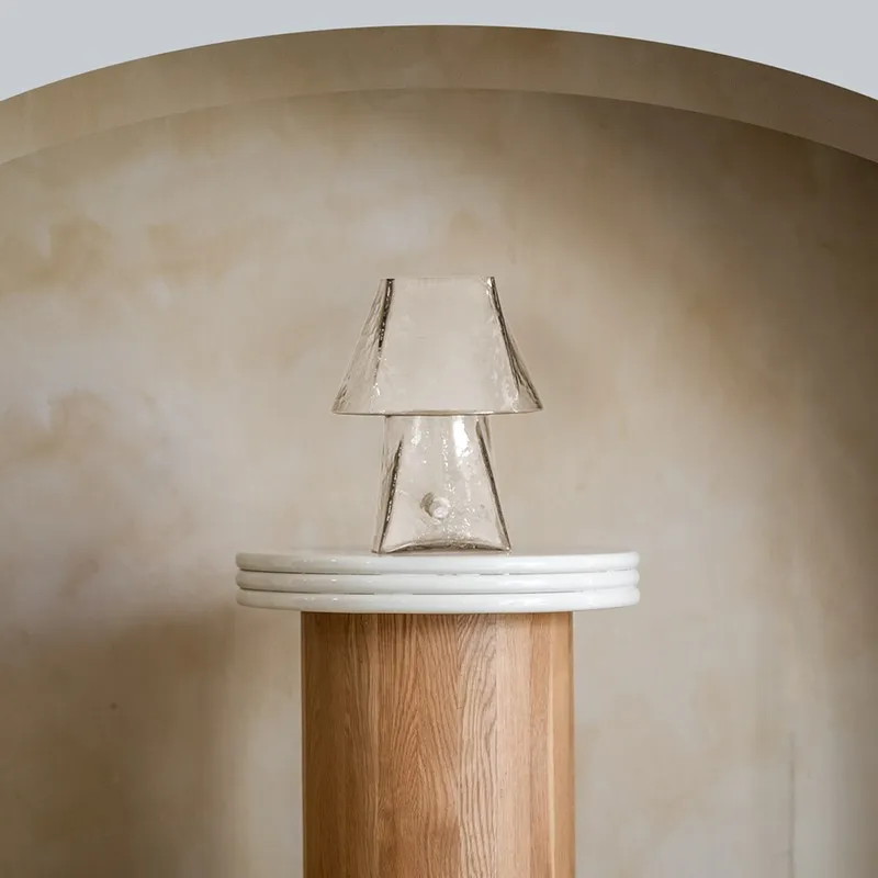 Clear glass table lamp styled on a tall pedestal