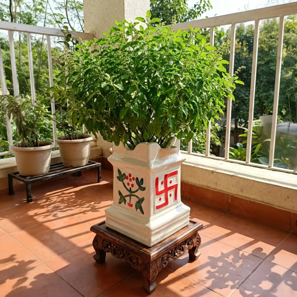 Decorated white ceramic planter with a leafy plant displayed on a balcony
