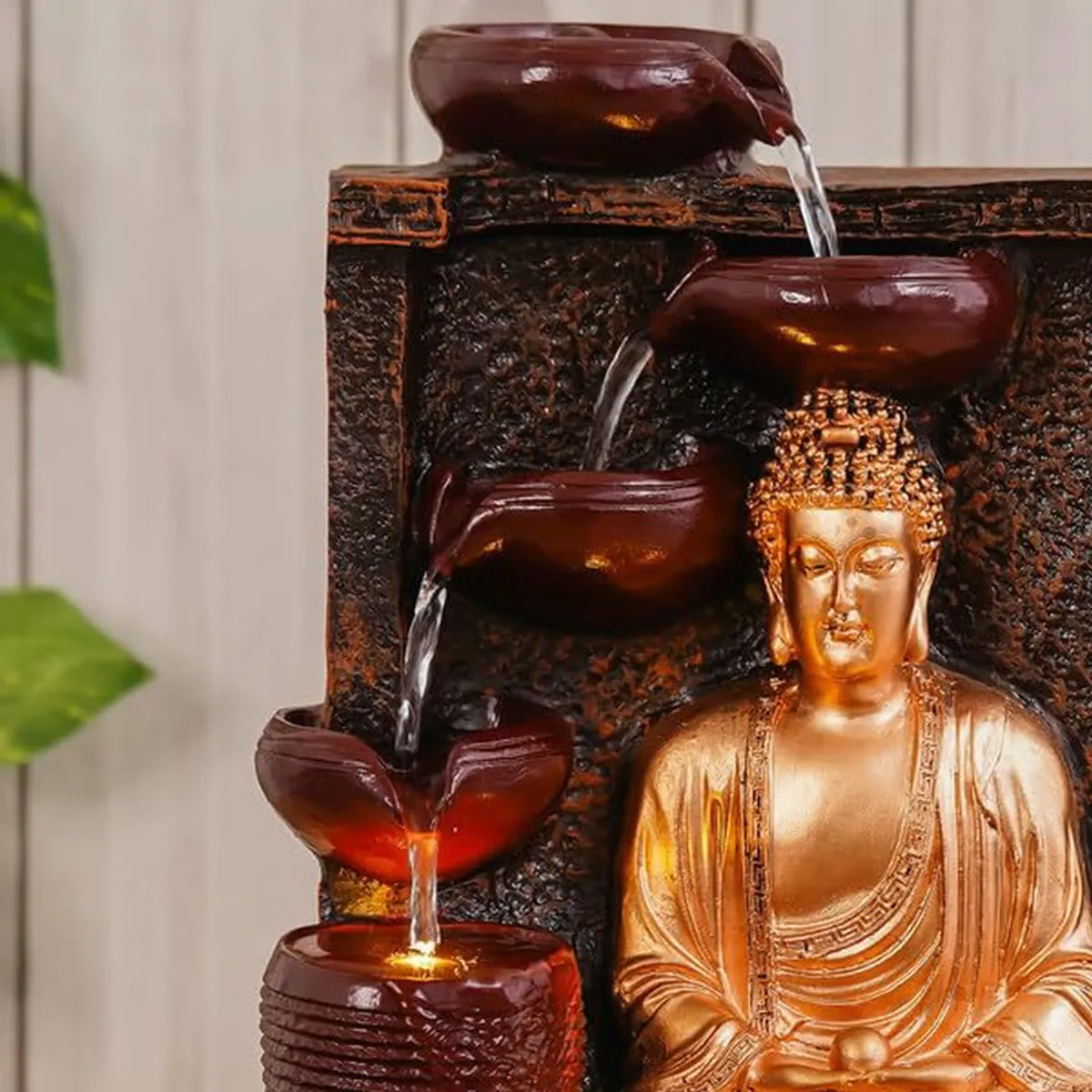 Close-up of Buddha fountain bowls, flowing water and warm LED glow