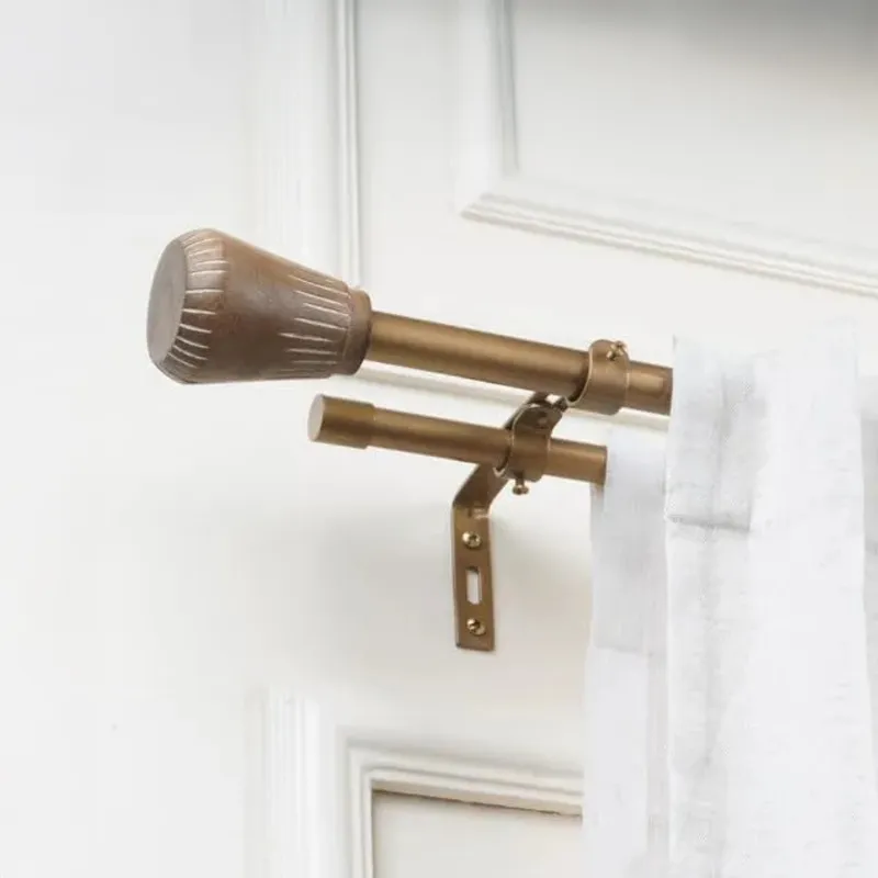 Double curtain rod with brown urn finial and wall bracket holding a sheer curtain
