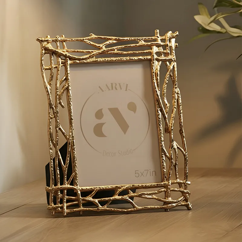 Gold rectangular photo frame with branch-like metal border on a wooden table