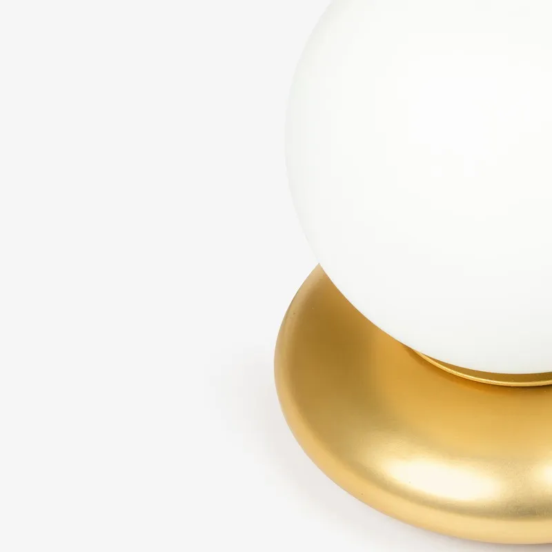 Close-up of white globe lamp resting on a rounded gold base