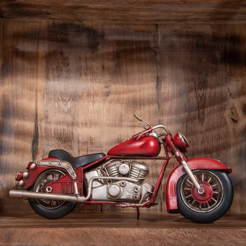 Full side profile of red vintage motorcycle showpiece on wooden shelf