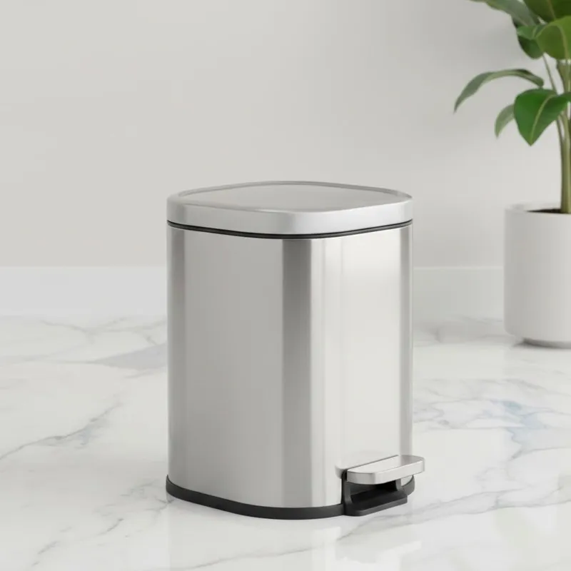 Silver metal dustbin with lid and pedal on a marble surface