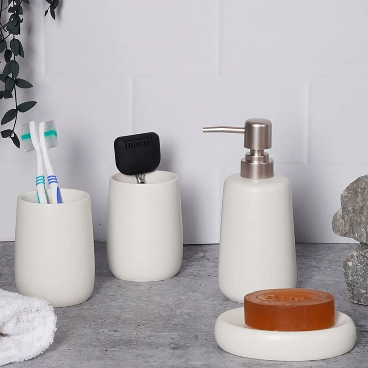 White ceramic bathroom accessories styled on a grey surface with a soap bar