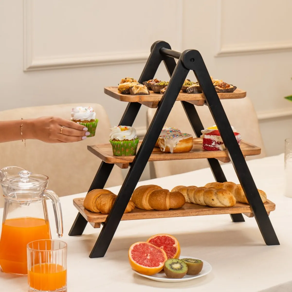 Three-tier wooden stand arranged with pastries, cupcakes and bread