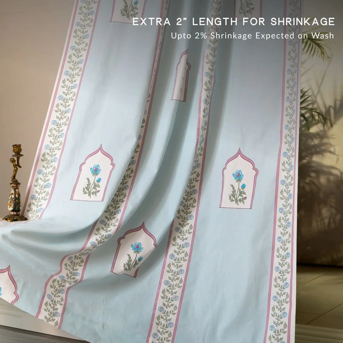 Light blue floral curtain fabric draped beside a decorative lamp.