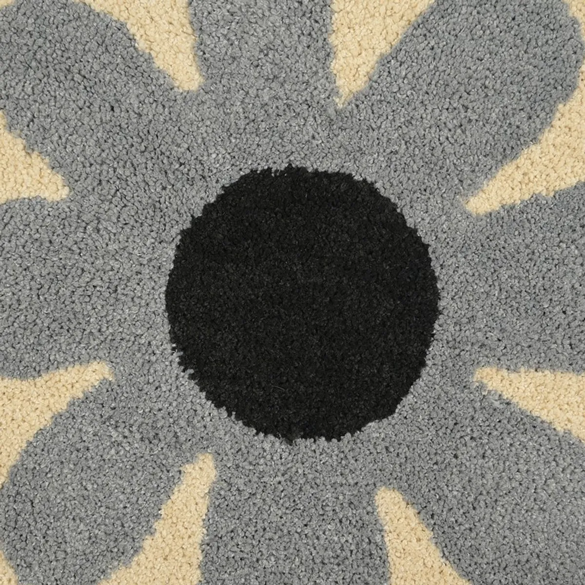 Close-up showing the black centre and plush grey floral texture of the bath mat.