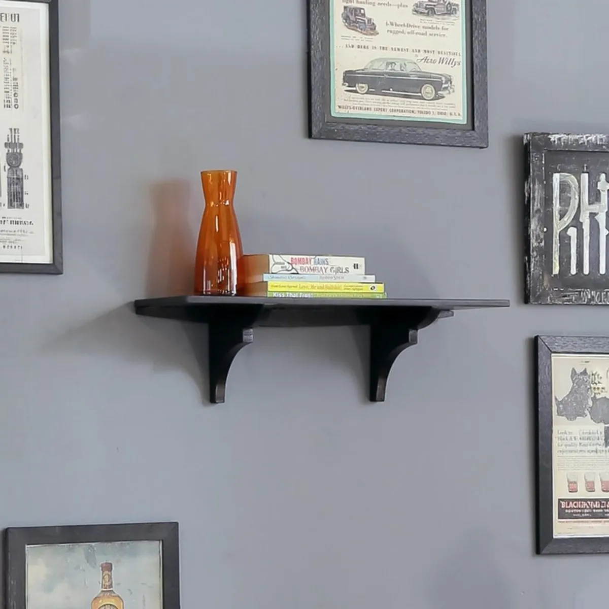Black wall shelf displayed on a grey wall with framed art and decor