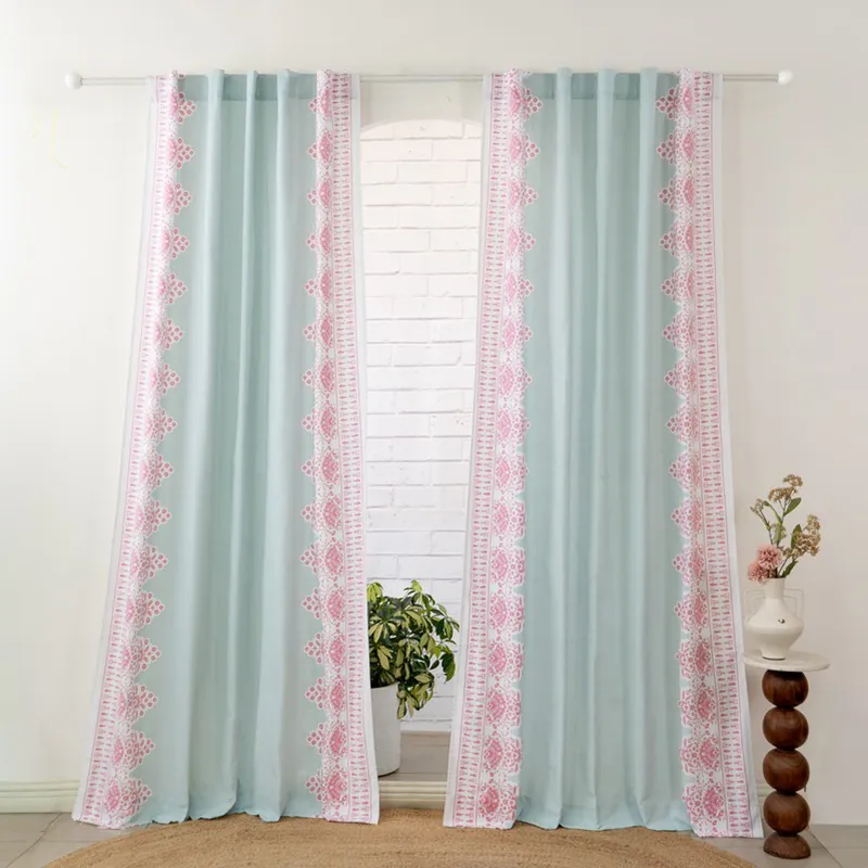Pair of aqua and pink floral curtains hanging from a rod in a bright room